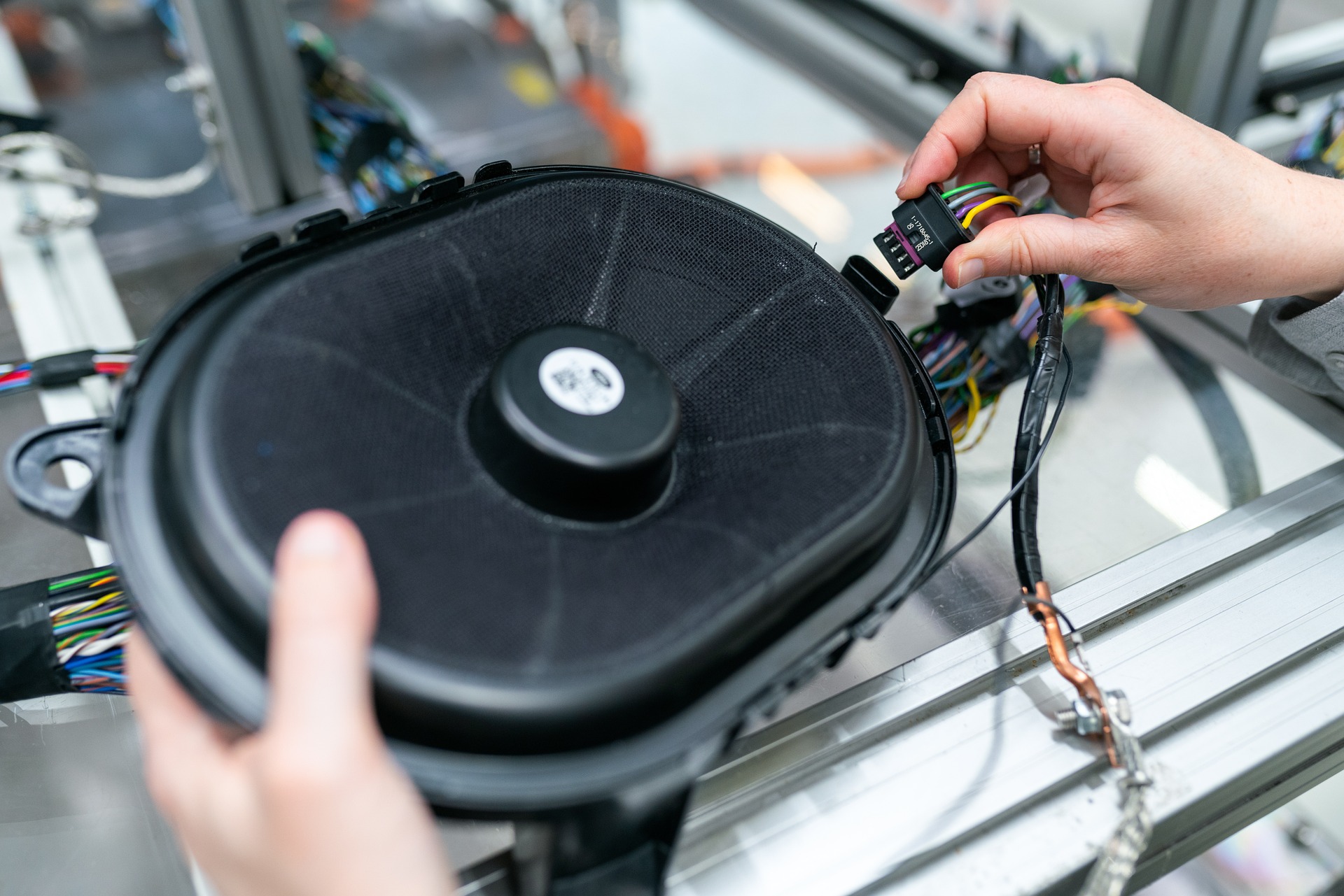 Hands connecting wiring to an electronic component in a machine.