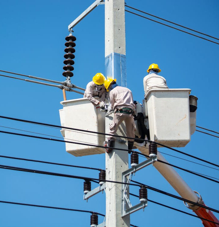 Workers in bucket lifts repairing power lines on a utility pole.