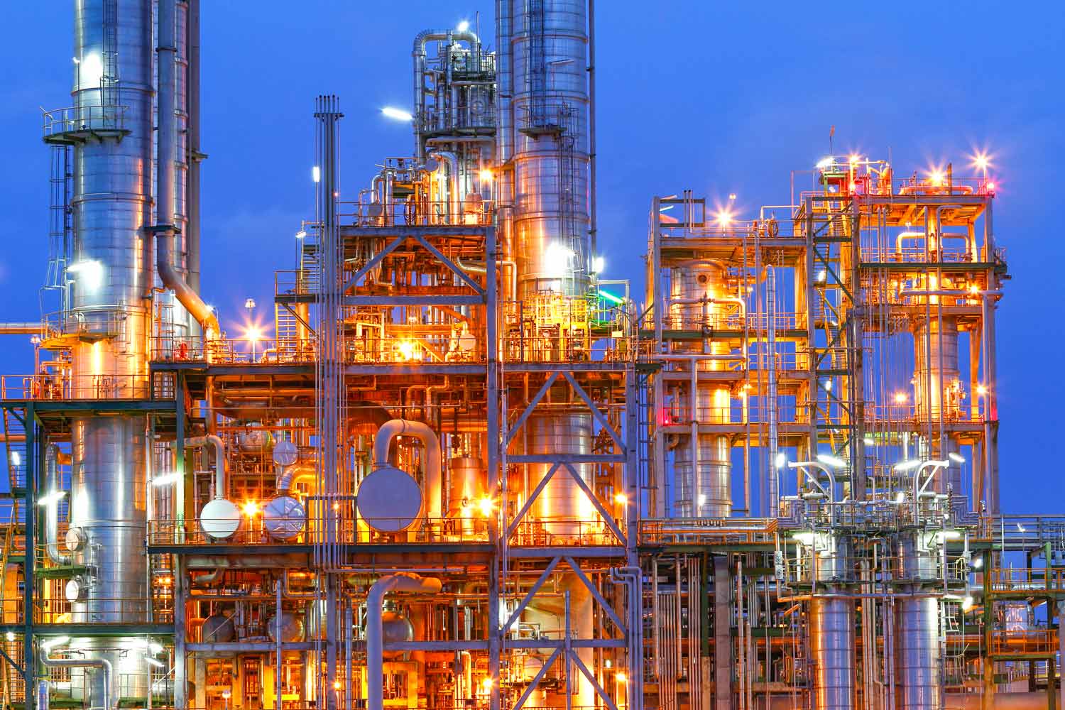 Industrial processing facility with illuminated process equipment and piping systems.